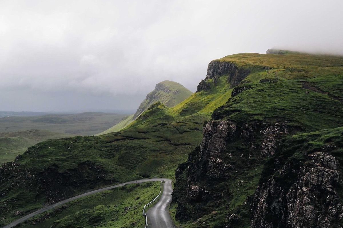 Green ridge with a road winding below it.