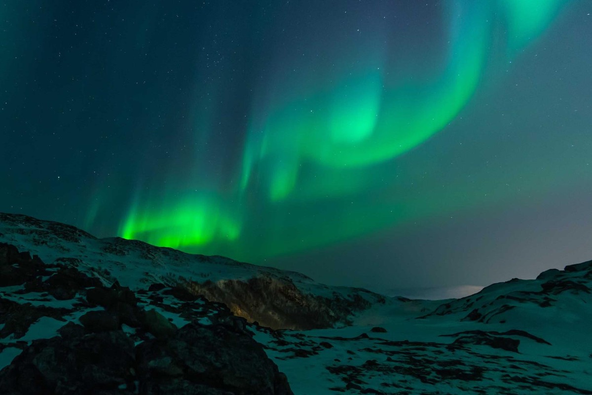 Northern lights over a snowy hillside.